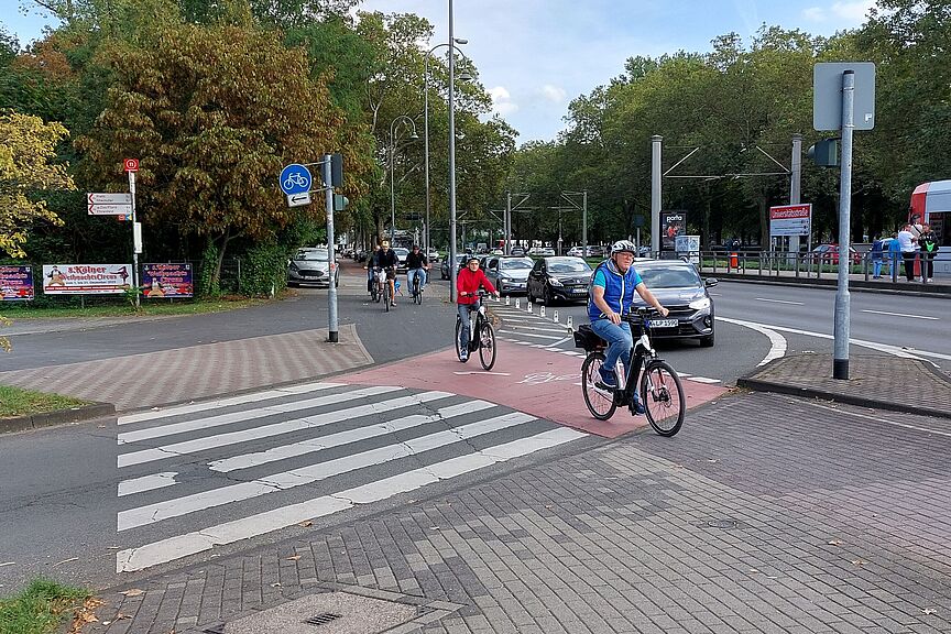 Safety first: Rot gefürbte Radwegfurt an einer Hauptverkehrsstraße in Köln Safety first: Rot gefürbte Radwegfurt an einer Hauptverkehrsstraße in Köln